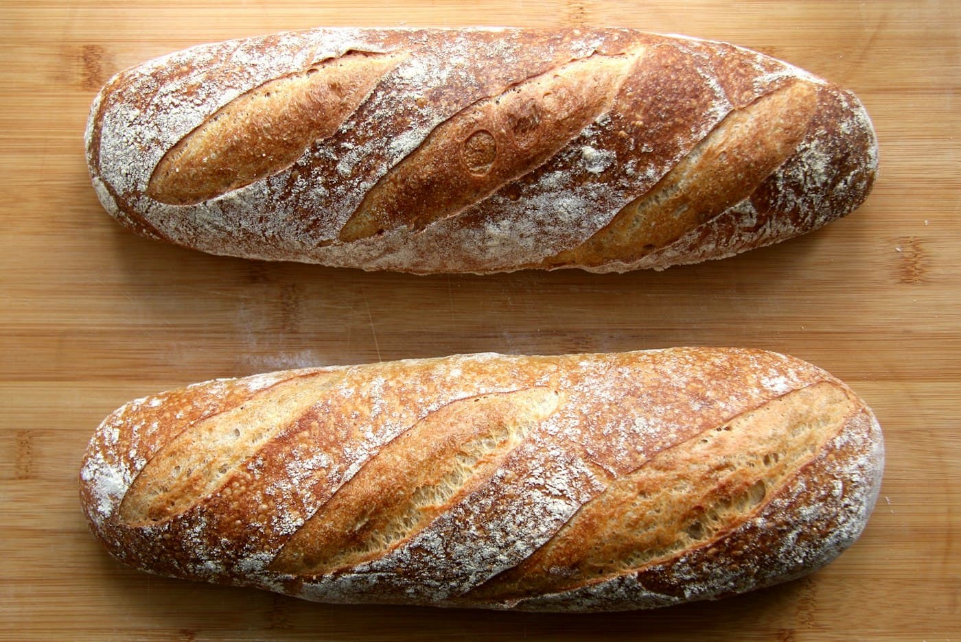 A flour-dusted sourdough loaf on a wooden board.